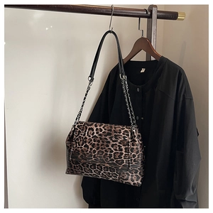 Détail d'un sac léopard avec bandoulière chaîne argentée et cuir synthétique marron texturé