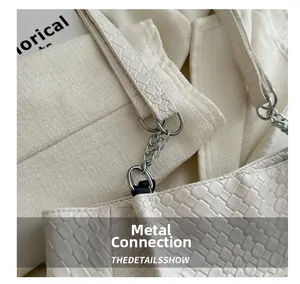Close-up of silver chain connection on a beige quilted weave tote bag with metal rings
