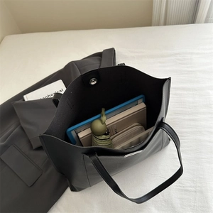 Internal view of black tote bag showing large capacity with laptop and umbrella inside