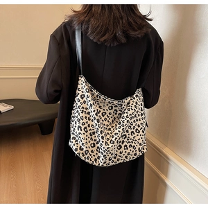 Détail du sac à bandoulière léopard porté par un mannequin dans un décor minimaliste