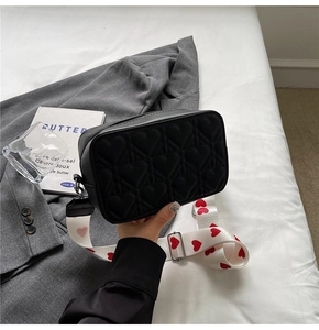 Détail du sac bandoulière noir matelassé cœur avec une large sangle élégante et moderne