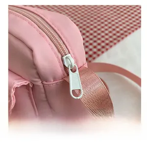 Macro detail of the smooth white metal zipper and durable pink nylon fabric of the bag