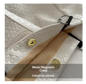 Detail shot of the golden magnetic hardware snap on a white quilted tote bag