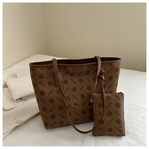 Close-up of brown textured tote bag with vintage monogram and matching small pouch