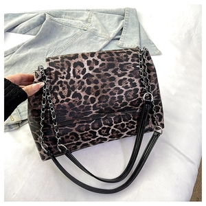 Détail du sac léopard avec bandoulière chaîne dorée sur fond de veste en jean