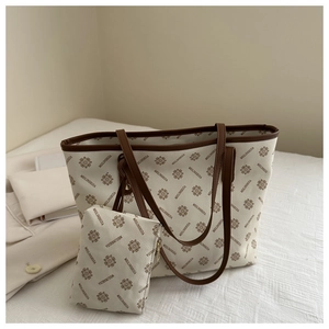 Close-up of beige monogram tote bag featuring vintage floral patterns and brown leather straps