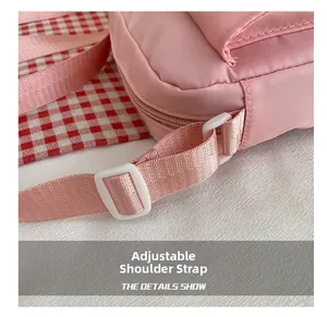 Detail showing adjustable shoulder strap with white resin buckle on pink crossbody bag