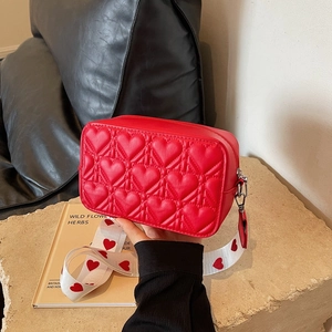 Sac bandoulière rouge matelassé cœur avec large sangle à motifs sur socle
