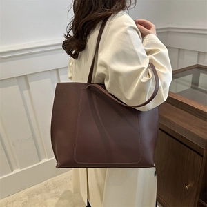Minimalist large brown leather tote bag with shoulder straps and front pocket for work
