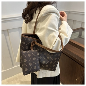 Detail of dark brown tote bag set with clover pattern and mini pouch on model shoulder