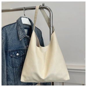 Detail of cream white tote bag with soft leather texture hanging against denim