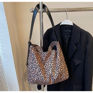 Gros plan d'un sac cabas en daim léopard avec bandoulière noire sur un cintre en métal