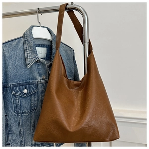 Detail of the brown wrinkled leather texture and wide strap on a large tote bag