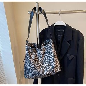 Détail du grand sac cabas en daim imprimé léopard suspendu à côté d'un blazer noir