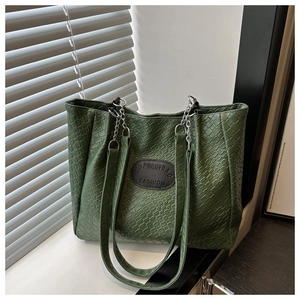 Detail of green woven texture tote bag with silver chain strap on a window sill