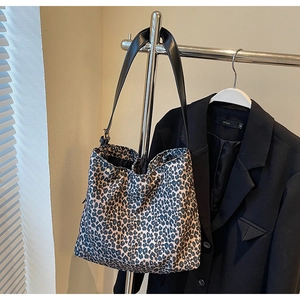 Détail d'un grand sac fourre-tout à motif léopard suspendu à côté d'une veste noire