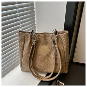 Close-up of beige quilted tote bag showing woven texture and elegant metal chain strap