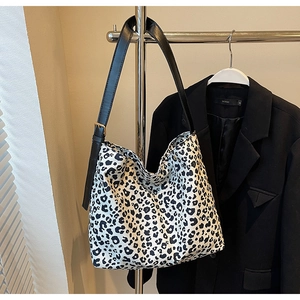 Détail de la bandoulière réglable en cuir noir et boucle dorée sur le sac à motif léopard
