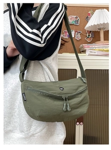 Olive green crescent nylon crossbody bag with adjustable strap shown on model's shoulder
