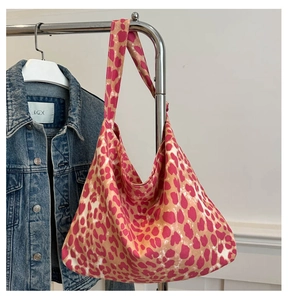 Detail view of pink and khaki leopard print canvas hobo bag on a denim jacket hanger