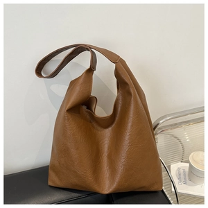 Macro shot of large vintage brown leather tote bag with subtle pebbled texture and strap