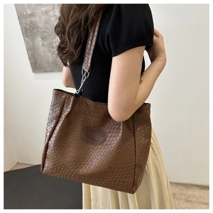 Detail of dark brown tote bag with woven texture and elegant metallic chain strap