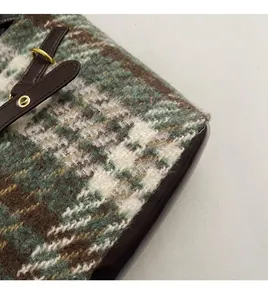 Détail du tissu en tweed à carreaux verts et de la bandoulière en cuir marron du sac