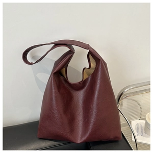 Detail view of burgundy tote bag with vintage wrinkled texture and wide shoulder strap