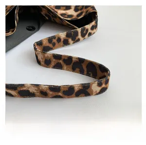 Detail of leopard print bag strap with black lining and secure snap button closure