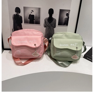 Detail showing pink and green canvas crossbody bags with sausage dog print and dog charms