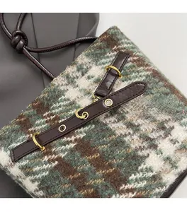 Détail de la texture en tweed à carreaux avec bordure en cuir et anneaux dorés du sac