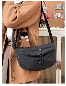 Detail of black nylon moon bag showing OK logo and adjustable shoulder strap on model
