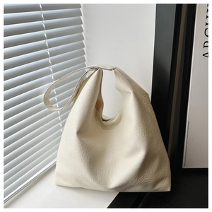 Detail view of cream white textured leather tote bag against a modern window scene