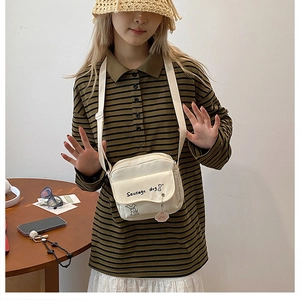 Detailed view of cream canvas crossbody bag featuring a cute sausage dog cartoon print