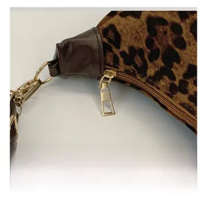 Gros plan sur la fermeture éclair dorée et le bracelet en cuir sur le sac léopard