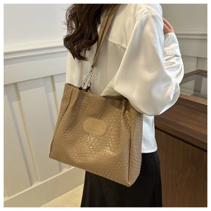 Detail of khaki woven pattern tote bag showing metallic chain strap and textured leather finish