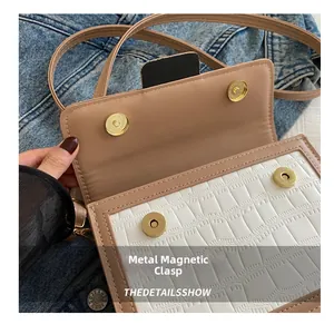 Detailed macro view of golden magnetic hardware closures on a stone texture crossbody bag