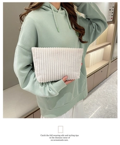 Détail de la pochette enveloppe en velours côtelé blanc avec étiquette rouge tenue