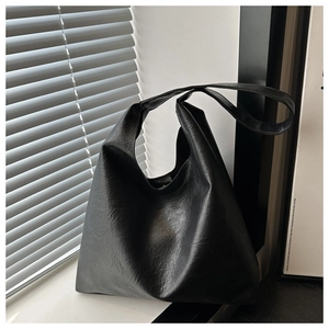 Close-up of black tote bag showing its wrinkled faux leather texture and wide shoulder strap