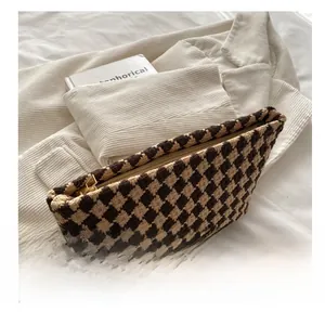 Close-up of brown and beige houndstooth woven pouch with a smooth golden metal zipper