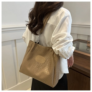 Detail of khaki quilted weave tote bag with silver chain strap on model for styling