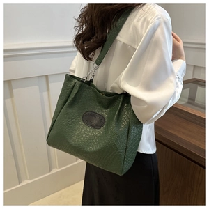 Detail of green woven tote bag with silver chain strap and logo patch on soft leather