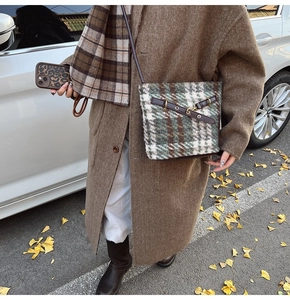 Photo de rue d'un grand sac cabas à carreaux avec lanières en cuir marron et boucles
