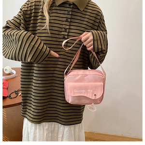 Close-up of pink crossbody bag with white sausage dog print and cute charm detail