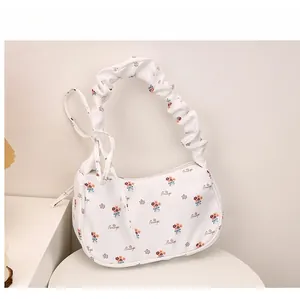 Detail view of floral crescent bag with decorative text and stylish ruched handle