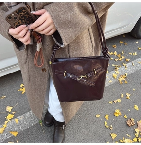 Détail du sac seau en cuir marron foncé avec boucle en métal rétro et feuilles de ginkgo