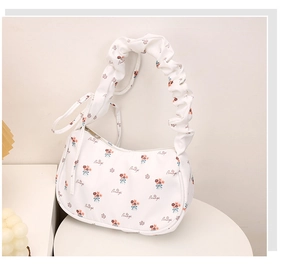 Detail of floral crescent bag featuring pleated strap and Beautiful text pattern
