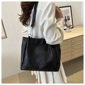 Close-up of black woven leather tote bag featuring elegant silver metal chain shoulder strap
