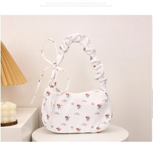 Close-up of floral canvas crescent bag with pleated handle and decorative bow detail