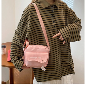 Detail of pink crossbody canvas bag with cartoon sausage dog print and bear charm